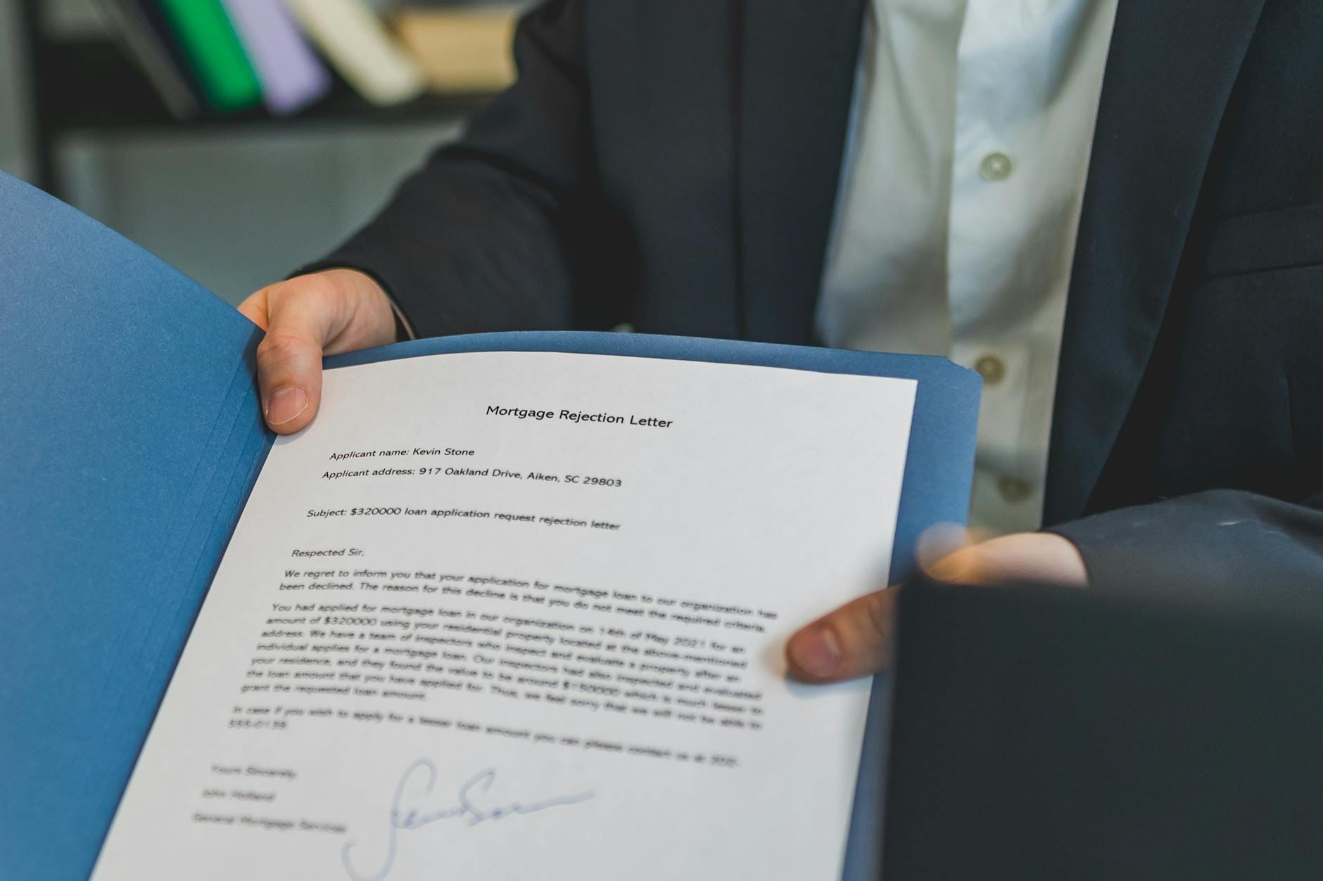 Osoba trzyma w teczce pismo o odrzuceniu wniosku kredytowego
