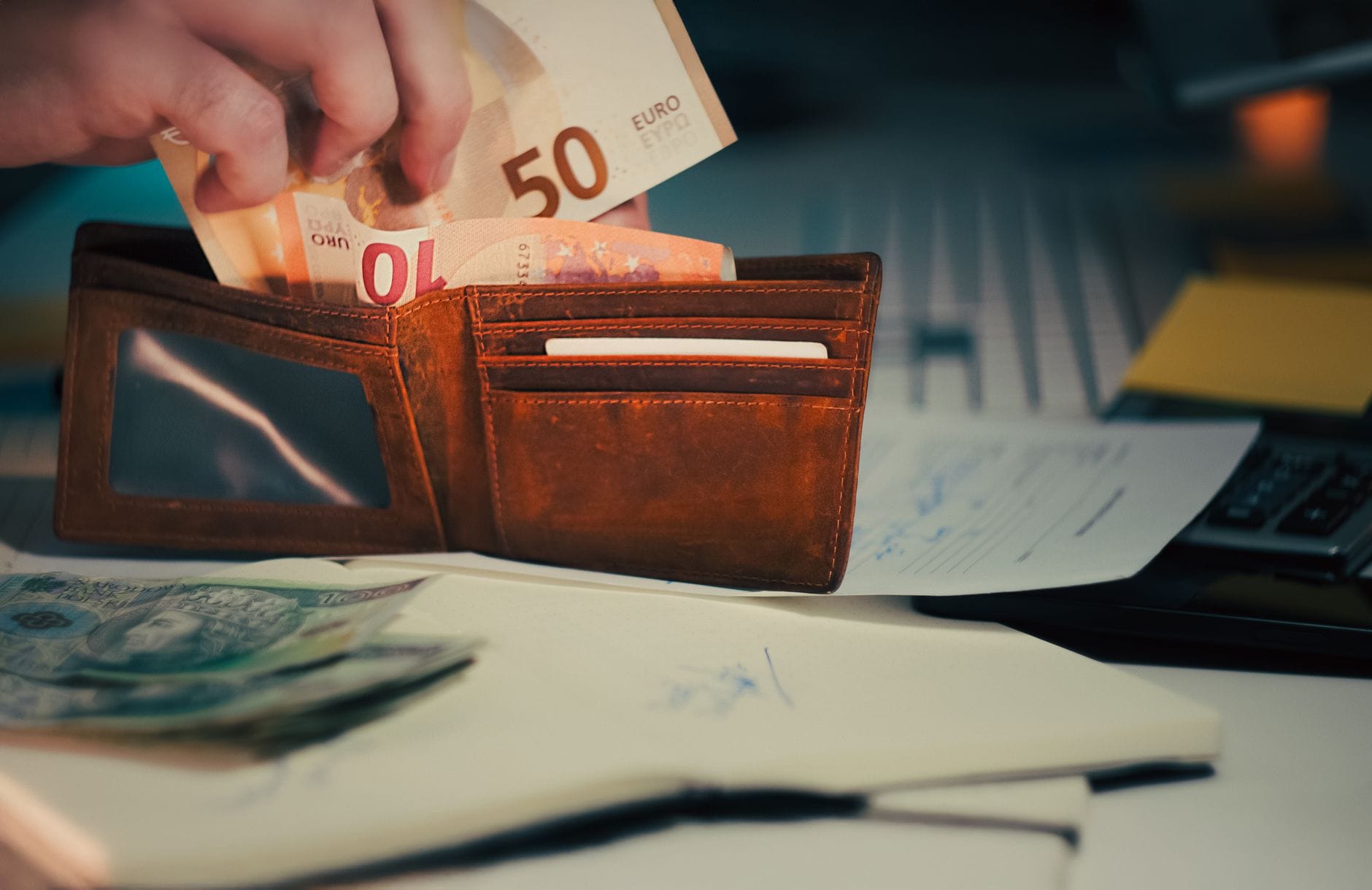 Portfel z banknotami euro i dokumentami na biurku przedsiębiorcy Portfel z banknotami euro i dokumentami na biurku przedsiębiorcy