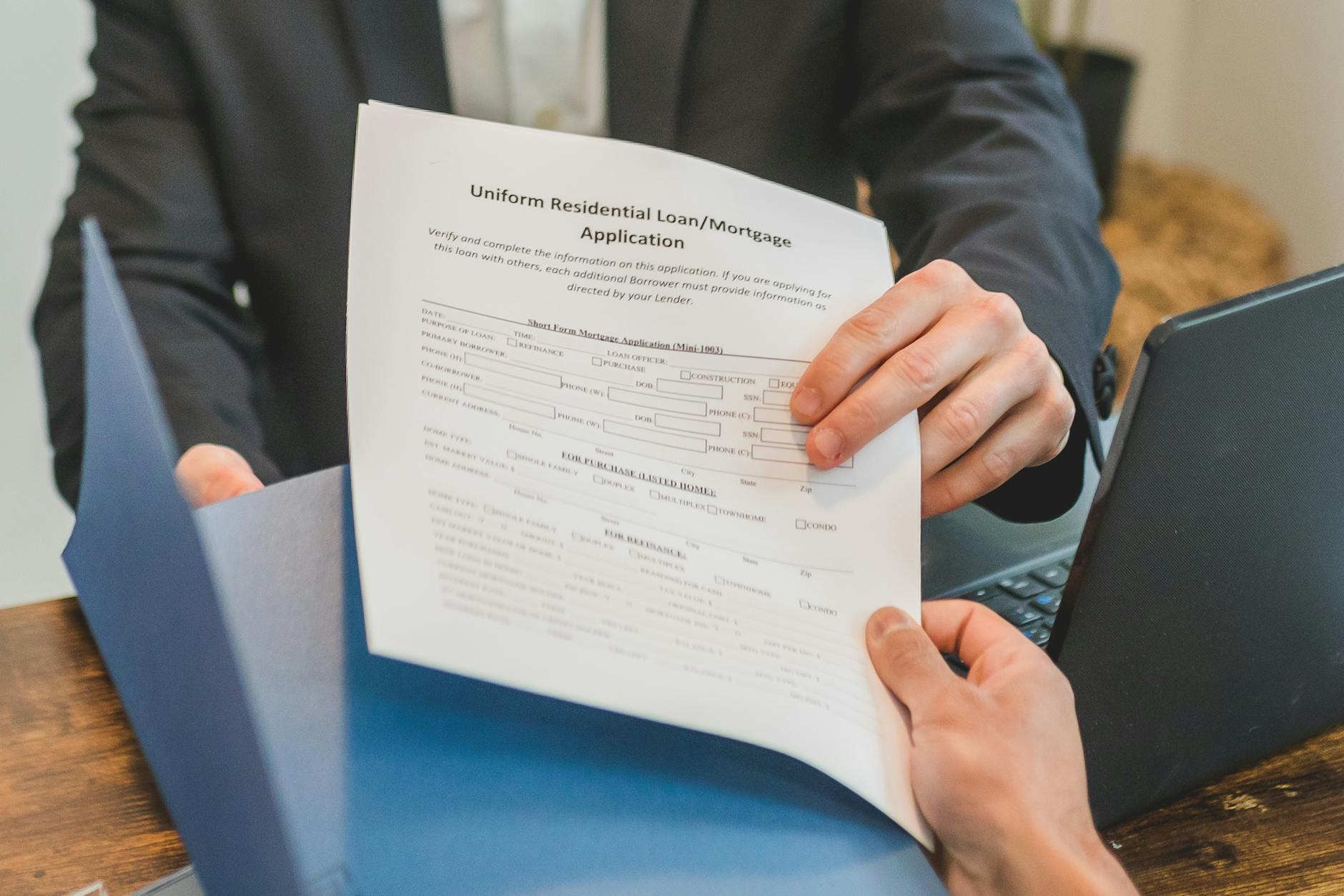 Czy bank widzi chwilówki w BIK i jak wpływają na ocenę wniosku kredytowego Przekazywanie wniosku kredytowego między dłońmi w biurze banku