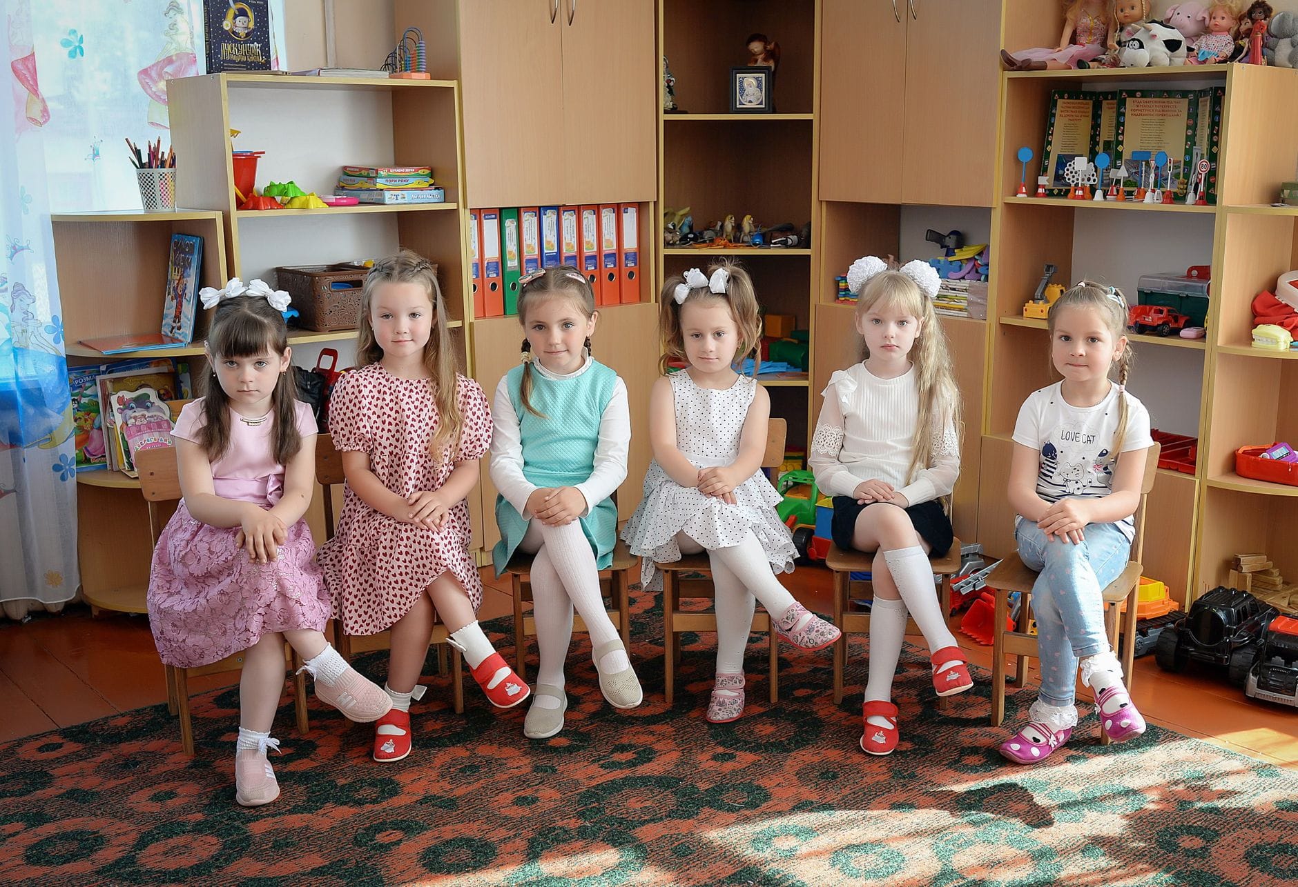 Dziewczynki bawiące się zabawkami na dywanie w sali przedszkolnej