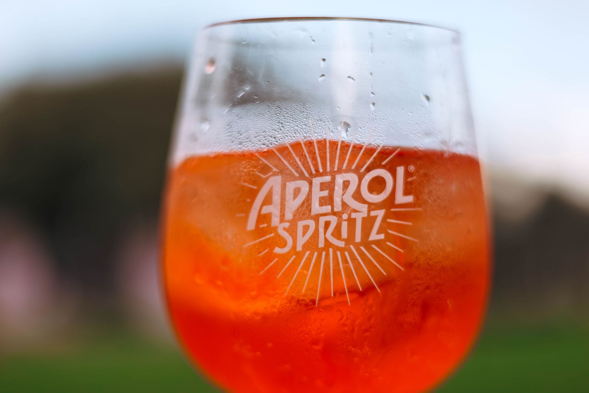 Aperitivo po włosku w Warszawie: jak stworzyć sycylijski klimat w domu Kieliszek Aperol Spritz w słońcu na tle rozmytego tarasu