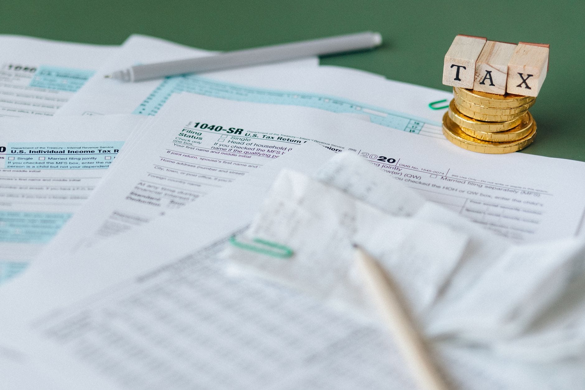 Stos formularzy podatkowych i monety z pieczątką TAX na biurku