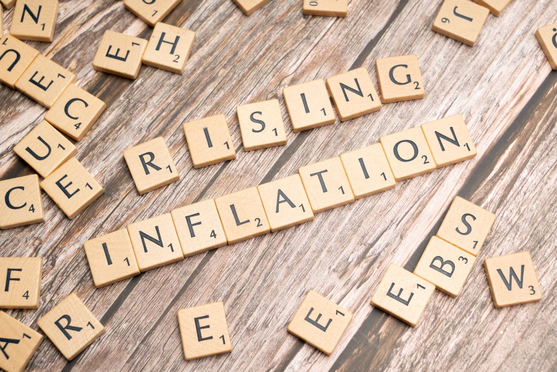 Drewniane kostki z napisem rising inflation na tle ekonomicznych wykresów