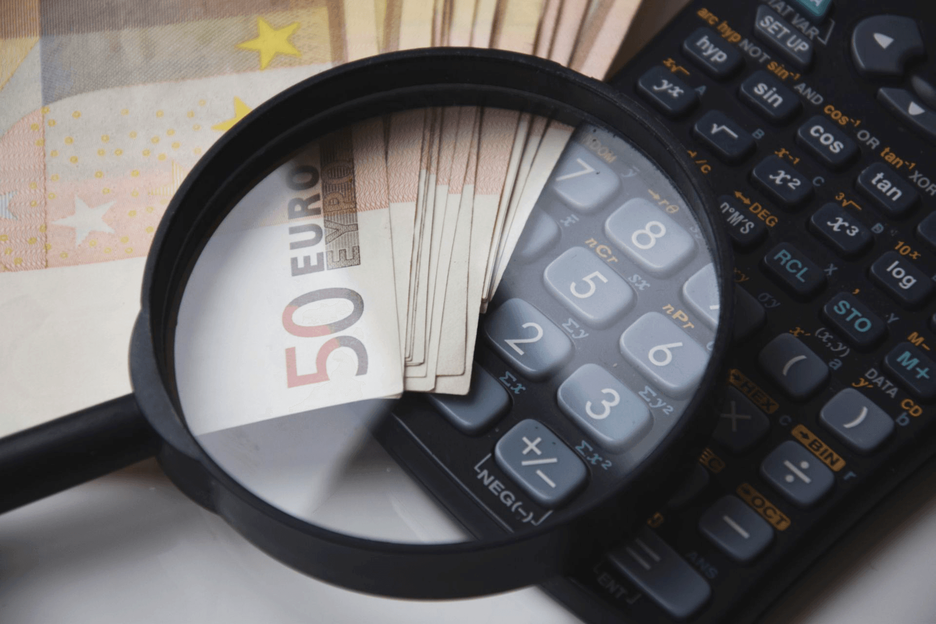 Lupa nad banknotami euro i kalkulatorem, analiza kosztów kredytu