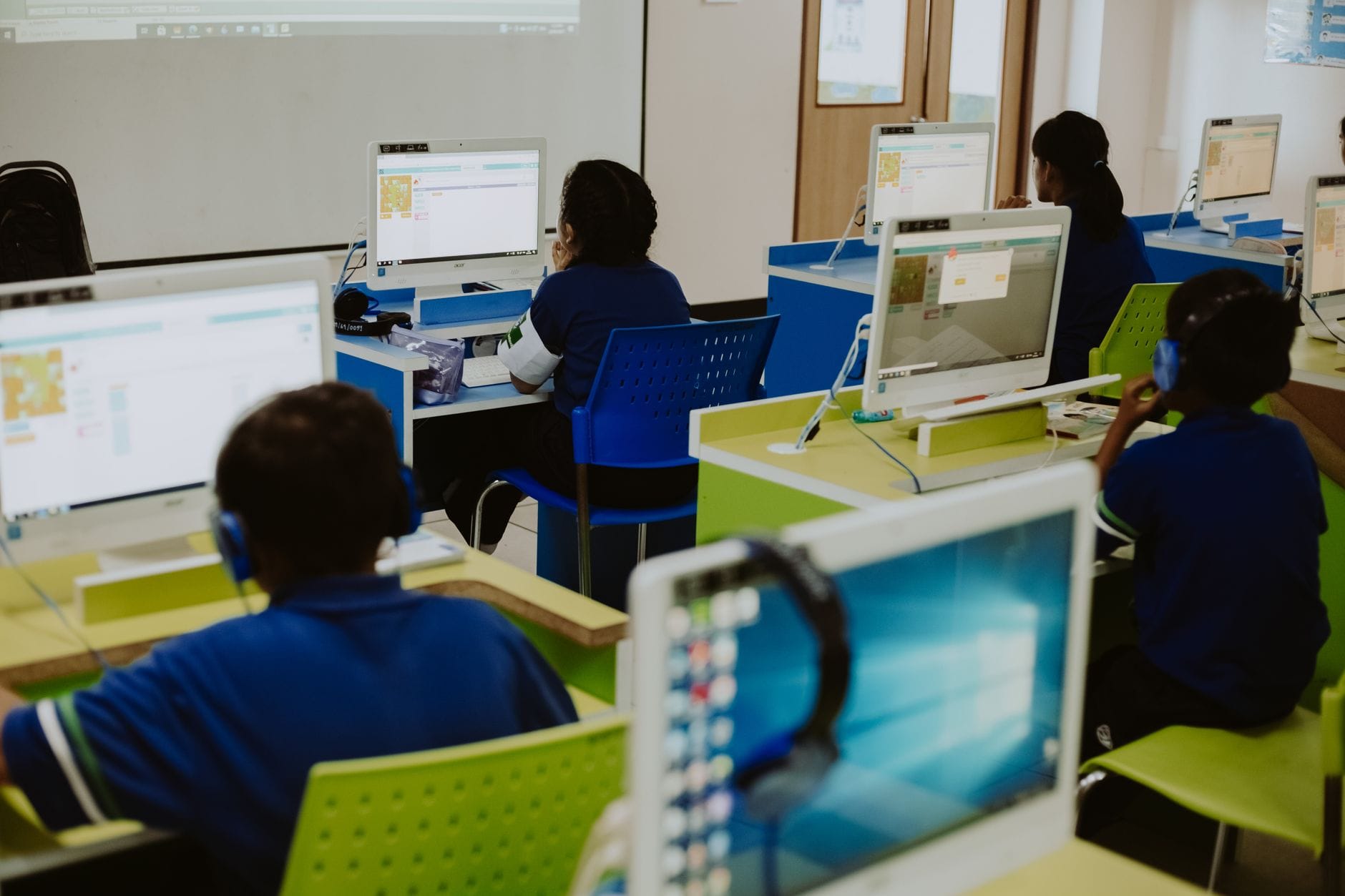 Uczniowie pracują przy komputerach w nowoczesnej szkolnej pracowni cyfrowej